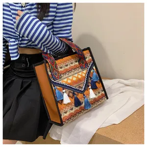 Dettaglio della borsa a shopper intrecciata etnica con motivi colorati e nappe pendenti.