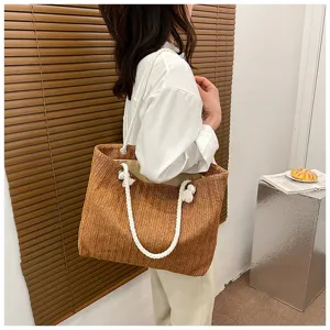 Detailaufnahme der Stroh-Shopper-Tasche mit strukturierter Oberfläche und weißen Kordelgriffen.