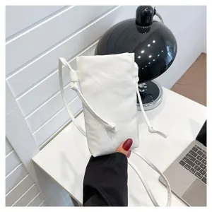 Vue de détail rapprochée d'un sac bandoulière pour téléphone en toile blanche minimaliste.
