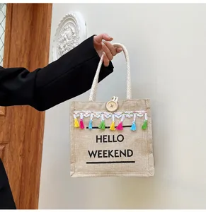 Détail du sac cabas en lin avec franges colorées, anses tressées et bouton en bois.