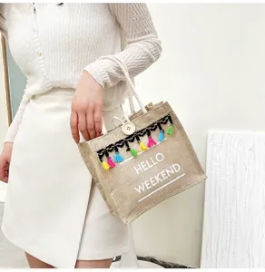 Sac cabas en jute tendance avec pompons colorés et imprimé, idéal pour l'été décontracté.