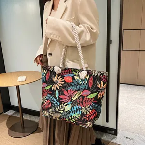 Detailansicht der Damen-Segeltuchtasche mit buntem Blumen-Blatt-Druck und praktischen Kordelgriffen.