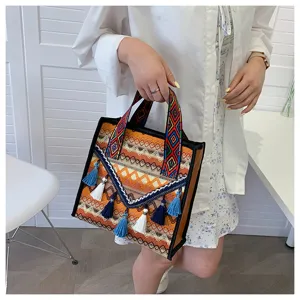 Vista dettagliata della borsa tote tessuta etnica con spallacci geometrici e nappe.