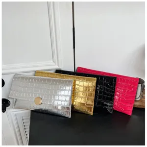 Vue détaillée de pochettes enveloppe multicolores à motif crocodile avec texture et fini métallique.