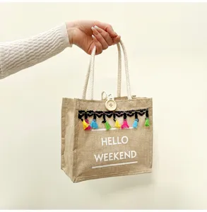 Vue rapprochée du sac à main en lin décontracté avec des pompons colorés et un bouton en bois.