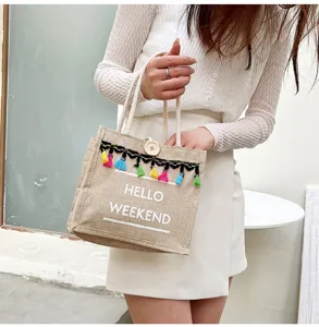 Vue détaillée du sac en lin avec des pompons colorés et un bouton en bois décoratif.