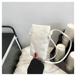 Gros plan détaillé d'un mini sac bandoulière de téléphone en toile blanche minimaliste.