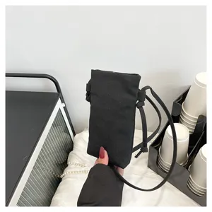 Sac bandoulière minimaliste en toile noire pour femme avec sangle fine pour un usage quotidien.