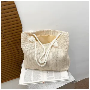 Nahaufnahme einer beige geflochtenen Strohtasche mit weißen Seilgriffen und Innenfutter.