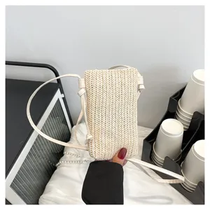 Vue détaillée d'un sac bandoulière chic en paille crème avec une bandoulière fine.