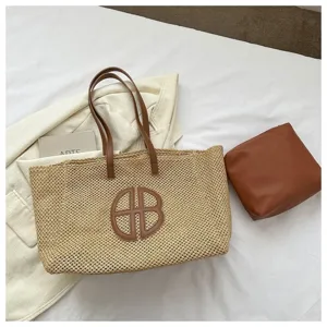 Close-up detail of the woven straw tote bag with brown leather handles and matching pouch.