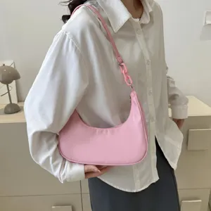 Détail de sac porté épaule en nylon rose avec bandoulière chaîne et fermeture zippée.