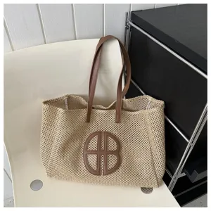 Detailed view of large woven straw tote bag, casual beach handbag with leather handle and patch.