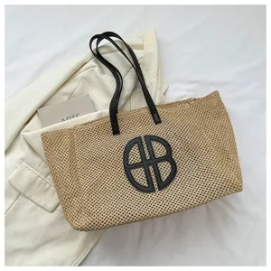 Large capacity woven straw beach bag with black handles and round monogram for summer vacation.