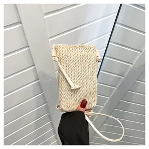 Gros plan détaillé du mini sac bandoulière de téléphone en paille tissée, montrant texture et design.