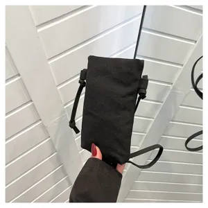 Vue détaillée d'un sac bandoulière pour téléphone en toile noire avec des lanières fines.