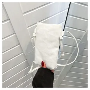 Gros plan détaillé du sac bandoulière minimaliste en toile blanche pour téléphone avec fine sangle.