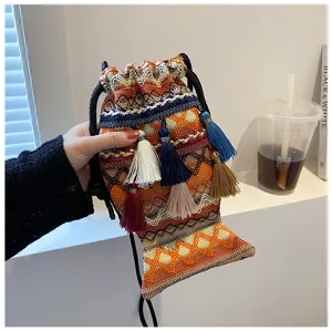 Détail en gros plan du sac bandoulière ethnique tissé à franges avec des motifs géométriques.