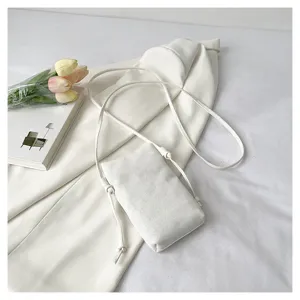 Vue détaillée du sac bandoulière blanc en toile pour téléphone, mini sac d'épaule minimaliste.