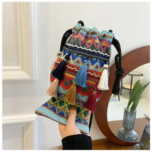 Vue détaillée du sac bandoulière tissé ethnique avec glands, motifs colorés et cordon de serrage.