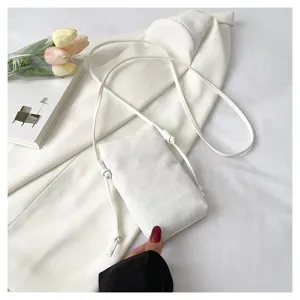 Vue détaillée d'un sac bandoulière minimaliste en toile blanche avec fine lanière.