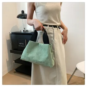 Vue rapprochée du sac à main décontracté en velours côtelé vert avec poignée noire.