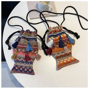 Vue détaillée du sac bandoulière ethnique tissé en forme de poisson avec des pompons colorés.