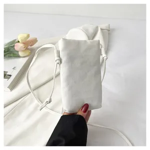 Gros plan d'un sac bandoulière pour téléphone en toile blanche simple avec une lanière fine.