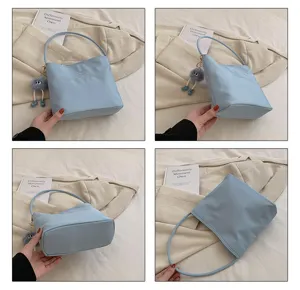 Vue rapprochée du sac porté épaule en nylon bleu clair avec pendentif peluche et broderie.
