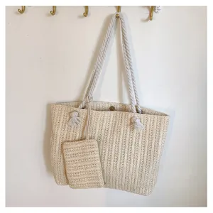 Détail du sac cabas en paille beige avec poignées en corde épaisse et sa petite pochette assortie.