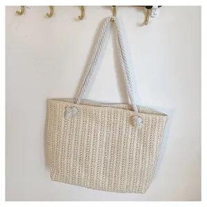 Sac cabas d'épaule en paille tissée beige avec poignées en corde et détails de nœuds.