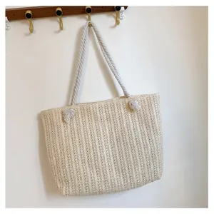 Vue détaillée d'un sac cabas en paille beige avec poignée en corde épaisse sur crochet.
