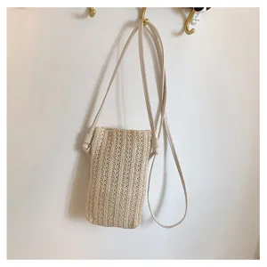 Vue détaillée d'un mini sac bandoulière tressé beige chic accroché au crochet mural.