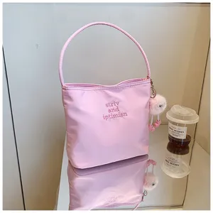 Vue détaillée du sac à main en nylon rose avec broderie raffinée et charmant pompon duveteux.