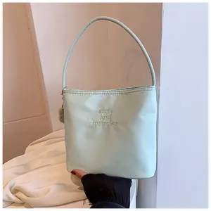 Vue détaillée du sac porté épaule en nylon vert menthe avec jolie broderie et breloque duveteuse.