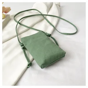 Vue rapprochée du sac bandoulière en toile verte montrant les lanières et la texture.
