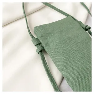 Gros plan détaillé du sac bandoulière minimaliste en toile verte avec sangle fine et nœud.