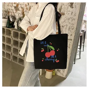 Detailopname van de zwarte canvas shopper tas met leuk kersengrafisch ontwerp.