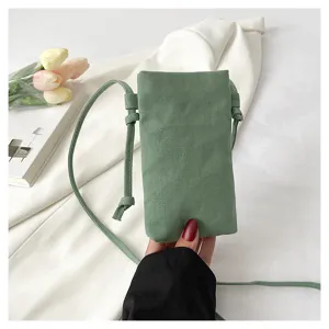 Détail de la pochette de téléphone en toile verte avec sa fine structure et bandoulière.