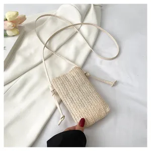 Vue détaillée de l'élégant sac bandoulière de téléphone en paille tissée beige fin.