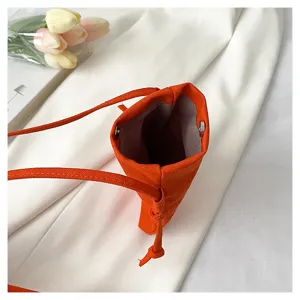 Vue détaillée d'un petit sac bandoulière de téléphone orange avec fermeture magnétique.