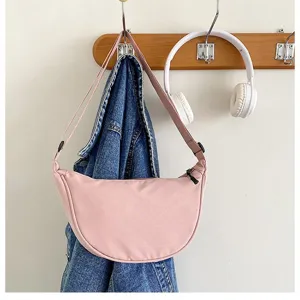 Gros plan sur un sac porte-epaule croissant en nylon rose, style decontracte quotidien.