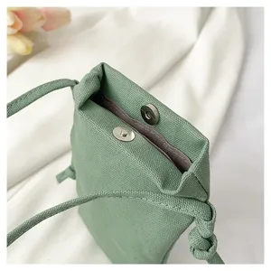 Détail de sac bandoulière en toile verte, sac de téléphone décontracté avec bouton aimanté.