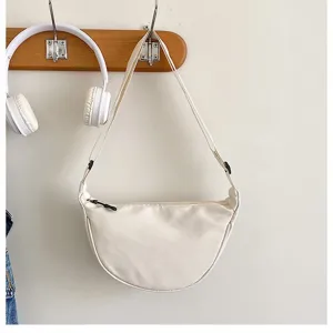 Détail de sac porté épaule minimaliste en nylon en croissant accroché au mur avec décors.