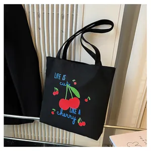 Detailopname van de casual zwarte canvas shopper tas met schattige kersenprint erop.