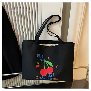 Close-up van zwarte canvas shopper tas met schattige kersenprint en Engelse tekst.