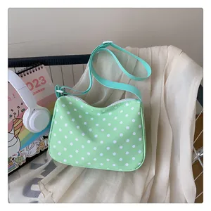 Detailweergave van de groene polkadot nylon schoudertas in een gezellige huiskamersfeer.