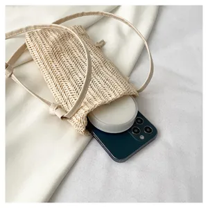 Vue détaillée du sac bandoulière de téléphone en paille avec lanière et compartiment.