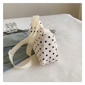 Gedetailleerd overzicht van de witte nylon crossbody tas met zwarte stippen en een riem.