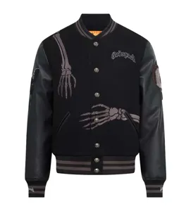 Detailed view of black streetwear varsity jacket with leather sleeves and skeleton embroidery.